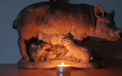 Eine Sau mit Ferkel, ein Kreuz, ein Teelicht
